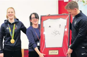  ??  ?? ●●Nicola hands over a signed shirt to teaching staff at the school