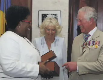  ?? / GETTY IMAGES ?? El príncipe Carlos y Camilla, duquesa de Cornualles, reciben una botella de ron local durante su reunión con la primera ministra de Barbados, Mia Mottley, en el Parlamento, en marzo de 2019, en Bridgetown (Barbados).