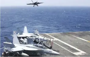  ??  ?? A US Navy F18 fighter jet lands on the US Navy aircraft carrier USS Carl Vinson (CVN 70) following a patrol off the disputed South China Sea. The USS Carl Vinson, which is steaming through the South China Sea, is just one of several high-profile...