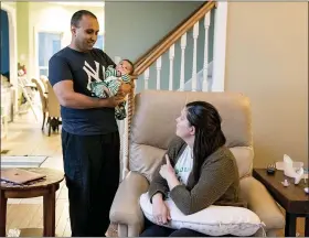  ?? WHITNEY CURTIS — THE WASHINGTON POST ?? ER physician Neal Patel holds his 3-month-old daughter, Lucy, as he talks to his wife, Katie Patel, after getting home from work at their home in Creve Coeur, Missouri, on Tuesday. Katie Patel, a nurse practition­er, is going back two work two weeks before her maternity leave is up.