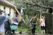  ?? CHRIS URSO — TAMPA BAY TIMES VIA AP ?? Steve Miccio secures a tree limb with a rope as he and others work to remove the tree from the roof of his Gulf Road home Tarpon Springs, Fla., Monday. Miccio and his family were not home at the time when the tree fell. Hurricane Irma brought heavy...