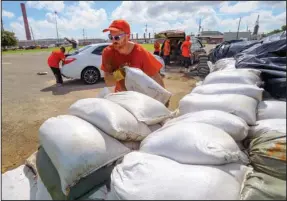  ?? The Associated Press ?? SANDBAGS: St. Bernard Parish Sheriff’s Office inmate workers move free sandbags for residents Thursday in Chalmette, La. Forecaster­s say Tropical Storm Barry is likely to become a Category 1 hurricane before making landfall today or early Saturday.