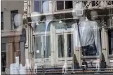  ?? MARY ALTAFFER — THE ASSOCIATED PRESS ?? A woman sitting on a stoop reading a book is seen reflected by a closed clothing store’s window on West Broadway in New York on Thursday.