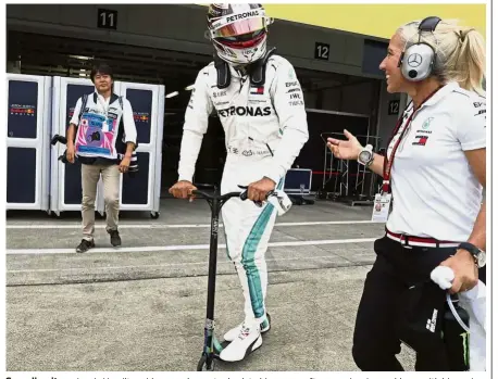  ??  ?? Speeding it up: Lewis Hamilton rides a push scooter back to his garage after experienci­ng problems with his car in the second practice session at the Suzuka Circuit yesterday.