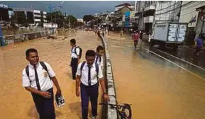  ?? REUTERS PIC ?? Students wading through a flooded street in Jakarta yesterday.