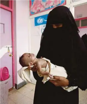  ?? [FOTO REUTERS] ?? Seorang ibu membawa anaknya yang mengalami masalah kurang zat ke pusat rawatan di Sanaa, Yaman.