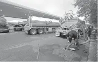  ?? AP Photo/Chuck Burton, File ?? ■ People wait in line as Travis Hall, right, and Brandon Deese, back, pump fuel from two tanker trucks at a convenienc­e store Sept. 17 in Wilmington, N.C.