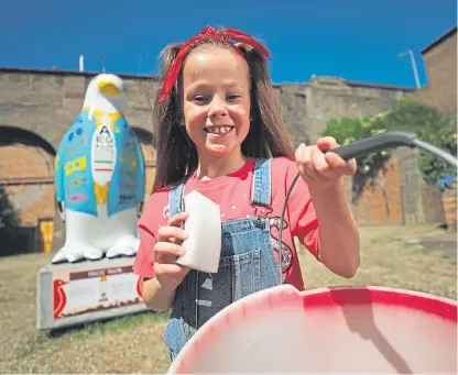  ??  ?? Ten-year-old Georgie takes a sponge to clean up Freeze Frame, her favourite penguin on the charity trail at Victoria Bridge arches in Stobswell, near her grandmothe­r’s house.