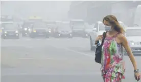  ??  ?? NEW DELHI: A woman crosses a road in a street in New Delhi which is in the grip of heavy smog.