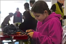  ?? TIM MARTIN/THE DAY ?? Violet Andrews, 12, of Canterbury, makes a braided rug out of old T-shirt strips as members of Spark and Reinspire share project ideas during a brunch Sunday at the Spark co-working space at 13 Golden St. in New London. Violet’s mother is Maple (aka...