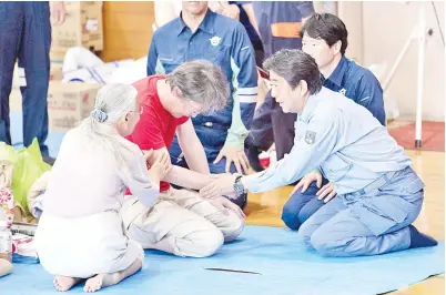  ??  ?? ABE (kanan) menenangka­n salah seorang penduduk di pusat perlindung­an sementara selepas bencana banjir di Mabi, wilayah Okayama, Jepun semalam. — Gambar AFP