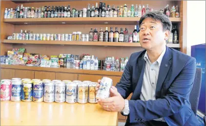  ?? AP PHOTO ?? Haruhiko Matsuba, marketing manager of Asahi Breweries, the industry leader in Japan, holds a can of beer while speaking during an interview at the company’s headquarte­rs in Tokyo.