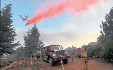  ?? JUSTIN SULLIVAN — GETTY IMAGES ?? A firefighti­ng aircraft drops fire retardant ahead of the River Fire as it burns through a canyon on Wednesday in Lakeport.