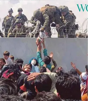 ?? AFP PIC ?? A United States Marine grabbing an infant over a fence of barbed wire during an evacuation at Hamid Karzai Internatio­nal Airport in Kabul on Thursday.
