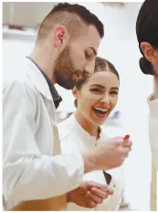  ?? STAFF PHOTOS BY MATT WEST ?? Olivia Culpo smiles during a lesson on leather craftsmans­hip from Luca Gabbi at the grand opening of TOD’s in Copley Place yesterday.