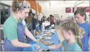  ??  ?? At the dissection table, Karaganne Burroughs, 6, of Hughesvill­e puts her finger inside a cow’s heart as her brother Kincade, 10, watches. Ashton Gordon, 14, a freshman at La Plata High School, helps out with her former teacher Jason Walent’s after...