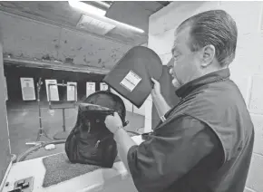  ?? MICHAEL WYKE/AP ?? Steve Naremore, founder and CEO of TuffyPacks, inserts a ballistic shield into a backpack before a demonstrat­ion of the product’s strength at the Shiloh Shooting Range in Houston on Friday.