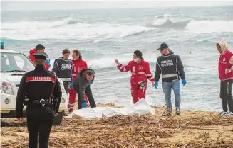  ?? Antonino Durso/Associated Press ?? Italian Red Cross volunteers and coast guards recover a body after a migrant boat broke apart in rough seas, at a beach near Cutro, southern Italy, on Sunday.