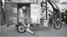  ?? Mark Schiefelbe­in / Associated Press ?? A courier sorts through deliveries in the back of his delivery cart along a street in Beijing.