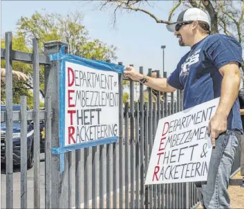  ?? L.E. Baskow Las Vegas Review-Journal @Left_Eye_Images ?? Jon Berry takes down a sign he attached to a fence after being told to do so by a security guard in front of the Sawyer Building during a June 12 protest.