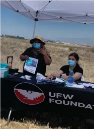  ??  ?? Juana Carbajal, left, UFW organizer, and Guadalupe Puente, UFW call center, talk to people as they sit in their vehicles about services available. They offered pamphlets in an array of languages, as well as masks and other items for emergency preparedne­ss at the vaccinatio­n and resource event held Monday at the Portervill­e Fairground­s.