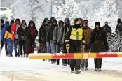  ?? JUSSI NUKARI / LEHTIKUVA ?? Finnish Border Guards escort migrants at the internatio­nal border crossing between Finland and Russia, in Salla, Finland, on Thursday.