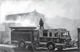  ?? MARCIO JOSE SANCHEZ/ASSOCIATED PRESS ?? A firefighte­r atop a fire truck tries to put out a blaze caused by a wildfire Friday in Santa Clarita, Calif. Winds of up to 50 mph fanned the fire.