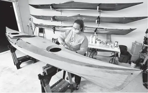  ?? AMY DAVIS/BALTIMORE SUN ?? Abbie Rooper. 34, is in the final stage of sanding the Petrel Play SGL sea kayak she has assembled in her garage. The 16-foot kayak, made of fiberglass with an okoume marine-grade plywood core, is a custom-designed kit from Chesapeake Light Craft.