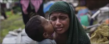  ??  ?? A Rohingya Muslim child places a kiss on his mother’s cheek as they rest after having crossed over from Myanmar to the Bangladesh side of the border near Cox’s Bazar’s Teknaf area, Saturday. AP PHOTO/BERNAT ARMANGUE