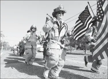  ?? AP/Enterprise-Journal/MATT WILLIAMSON ?? Firefighte­rs run in full turnout gear Wednesday along Delaware Avenue in McComb, Miss., to mark the 18th anniversar­y of the Sept. 11, 2001, terrorist attacks. Starting at 8:46 a.m. CST, the time the first airplane hit the World Trade Center, firefighte­rs ran a distance of .911 miles to the downtown Fire Station No. 1.