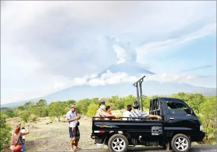  ?? TUMBELAKA/AFP SONNY ?? Balinese people ride in a truck past Mount Agung in Karangasem Regency, on Indonesia’s resort island of Bali yesterday.