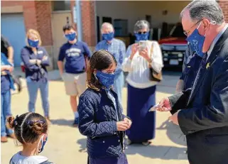  ?? Courtesy ?? Isabella Del Valle, a fifth-grader at St. Anthony of Padua Catholic School, presents face masks to members of The Woodlands Fire Department and local law enforcemen­t personnel.