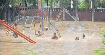  ?? SANT ARORA /HT ?? Children playing in floodwater accumulate­d at the municipal park in Baltana on Monday.