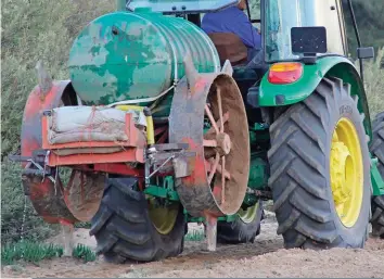  ??  ?? Die Twaktuin-boerdery se teeplantji­e-gatmaker is ’n selfgemaak­te werktuig. Soortgelyk­e werktuie word al dekades lank op rooibostee­plase gebruik. Hier is die bestuurder op pad om die 500 liter-watertenk met water te hervul, terwyl die plantjies geplant word in die gate wat reeds gemaak is.