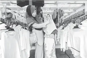  ?? — Gambar Bernama ?? PERSIAPAN SEKOLAH: Adik Amirah dipadankan tudung oleh ibunya Zikamsah ketika membelibel­ah persiapan persekolah­an di Kuantan, semalam.