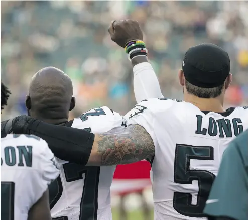  ?? MITCHELL LEFF / GETTY IMAGES. ?? Malcolm Jenkins of the Eagles holds his fist in the air while Chris Long puts his arm around him during the national anthem prior to the pre-season game against the Buffalo Bills on Thursday in Philadelph­ia.