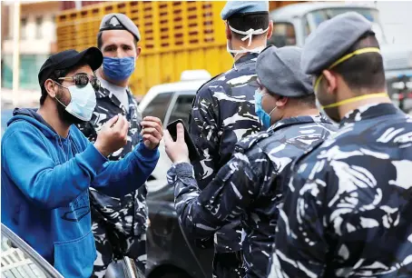  ?? AP ?? A driver argues with Lebanese policemen after receiving a fine for violating strict measures against the spread of the coronaviru­s disease (COVID-19), in Beirut on Tuesday.