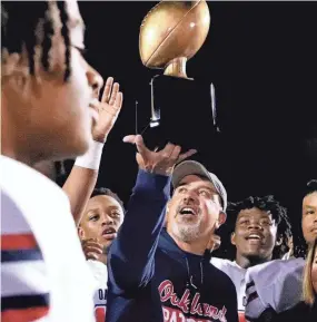  ?? HELEN COMER/THE DAILY NEWS JOURNAL ?? Oakland head coach Kevin Creasy holds up the Friday Night Rivals Champions Trophy after beating Riverdale.