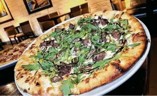  ??  ?? The S&M pizza incorporat­es sirloin steak, mushrooms, white sauce, arugula and balsamic reduction at Embers Wood Fire Kitchen & Tap in Stone Oak.
