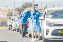  ?? ( Yossi Aloni/ Flash90) ?? CLALIT HEALTH care workers take test samples at a drive- through site for coronaviru­s testing in Lod on Friday.