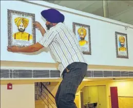  ?? HT PHOTO ?? A worker installing portraits in a gallery dedicated to martyrs of the Saragarhi battle at a serai by that name, managed by the SGPC, in Amritsar.