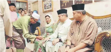  ??  ?? One of the community leaders performing the Tepung Tawar on Awang Tengah (second right) as Dayang Morliah (on his right) and others look on.