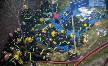  ??  ?? Völlig erschöpft: Londoner Feuerwehrl­eute starren auf die Überreste des qualmenden Hochhauses. Gegen die Flammenwan­d ha ben sie nur wenig ausrichten können.