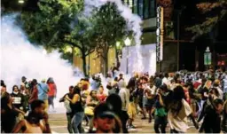  ??  ?? People run from flash-bang grenades during a protest in downtown Charlotte yesterday.