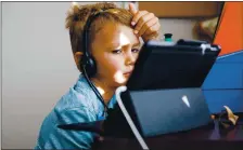  ??  ?? Colin Davis, 7, concentrat­es during his online class hosted via videoconfe­rence during his first day of school at his San Jose home on Wednesday.