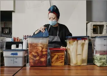  ?? PHOTOS BY ADAM AMENGUAL — THE NEW YORK TIMES ?? Jihee Kim checks on veggies at various stages of fermentati­on for Perilla, her popup takeout kitchen in Los Angeles.