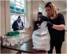  ??  ?? Volunteers prepare grab-and-go meals at Caritas Community Center on Tuesday. Caritas has been offering free meals since March 18.