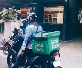  ??  ?? Grab delivery worker Dinh Van Hung making a stop in the busy city of Hanoi, Vietnam.