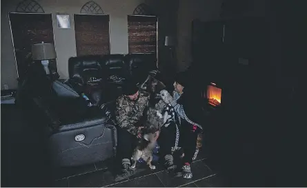  ?? COURTNEY SACCO/ USA TODAY NETWORK ?? Fernando and Marissa Cisneros and their dogs stay warm under blankets by a heater as Texas shivers and millions are without power. The state had been warned of deficiencies in its grid.