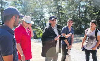  ??  ?? Randy Chipps, centre, an elder from the Beecher Bay (Scia’new) First Nation, talks with the group of Syrian refugees on the trails of East Sooke Park.